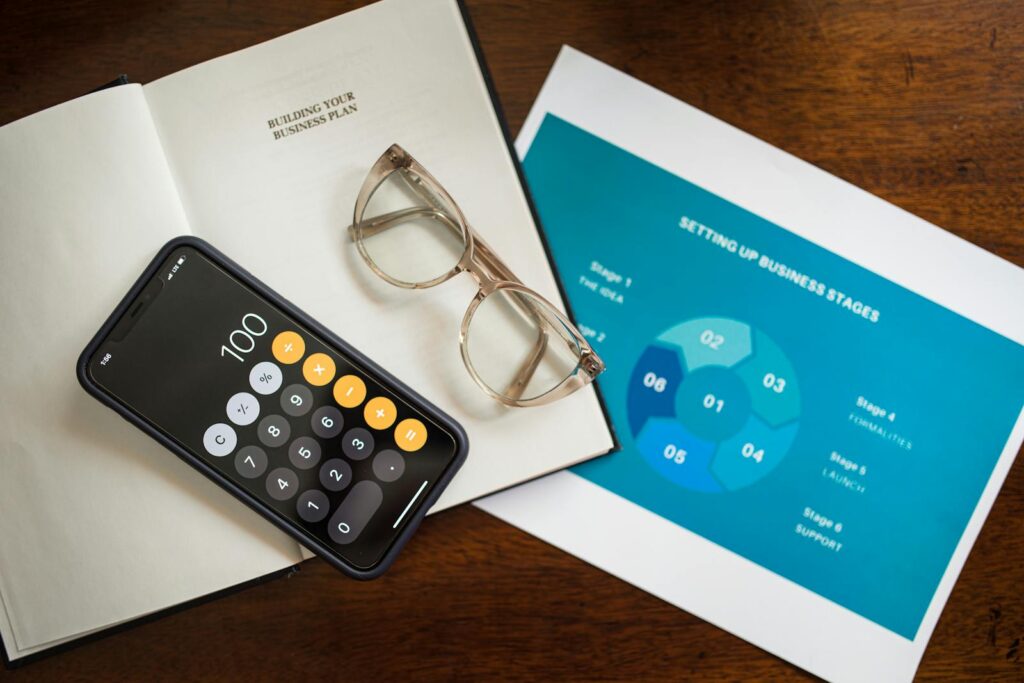 Open notebook, smartphone, and eyeglasses on a desk for business planning.